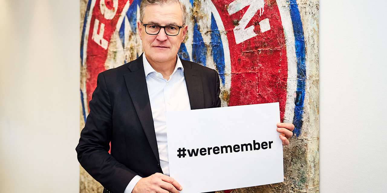 Jan Christian Dreesen, Vorstandsvorsitzender des FC Bayern, zeigt mit ernster Miene ein Banner mit der Aufschrift "weremember" in die Kamera