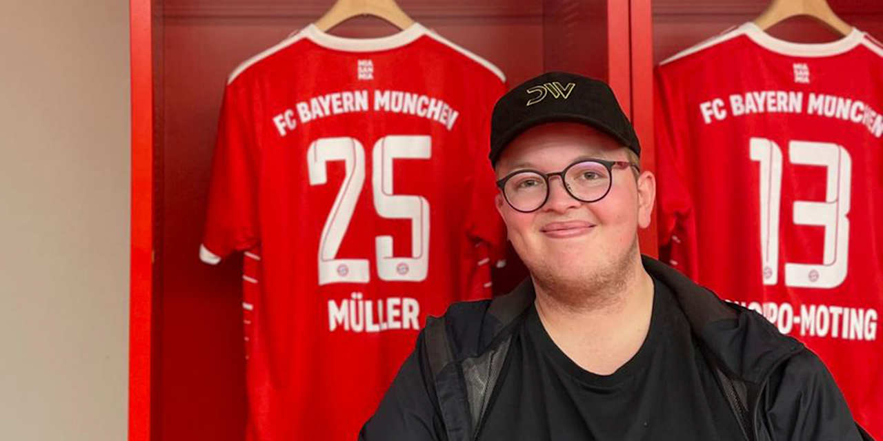 FC Bayern-Fan Glenn sitzt in der Kabine der Allianz Arena vor einem Trikot von Thomas Müller