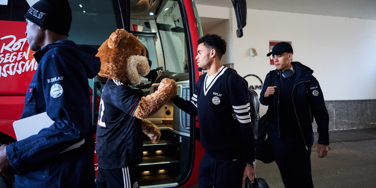 Luis Díaz und Jamal Musiala in blauen Replay-Outfits steigen in den Bus.
