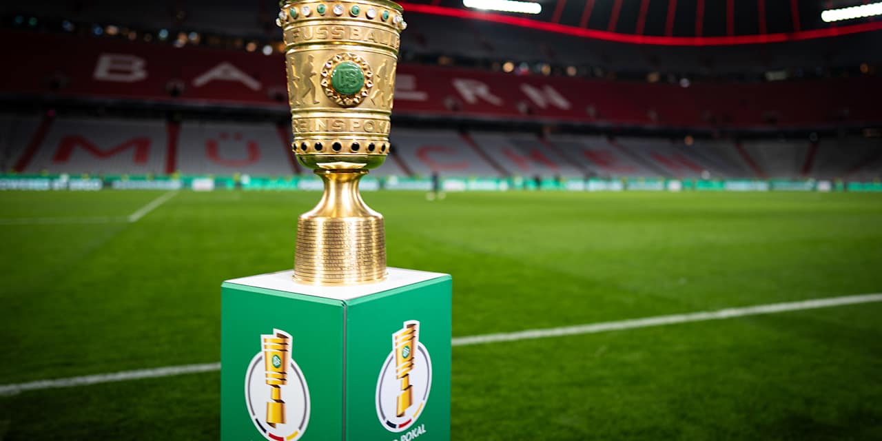Trophäe des DFB-Pokals auf einem Podest vor dem Rasen in der Allianz Arena
