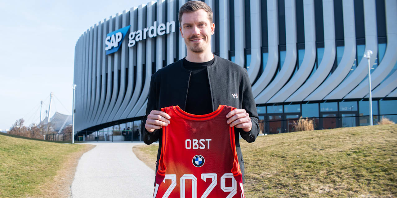Andreas Obst hält ein Trikot vor dem SAP Garden hoch