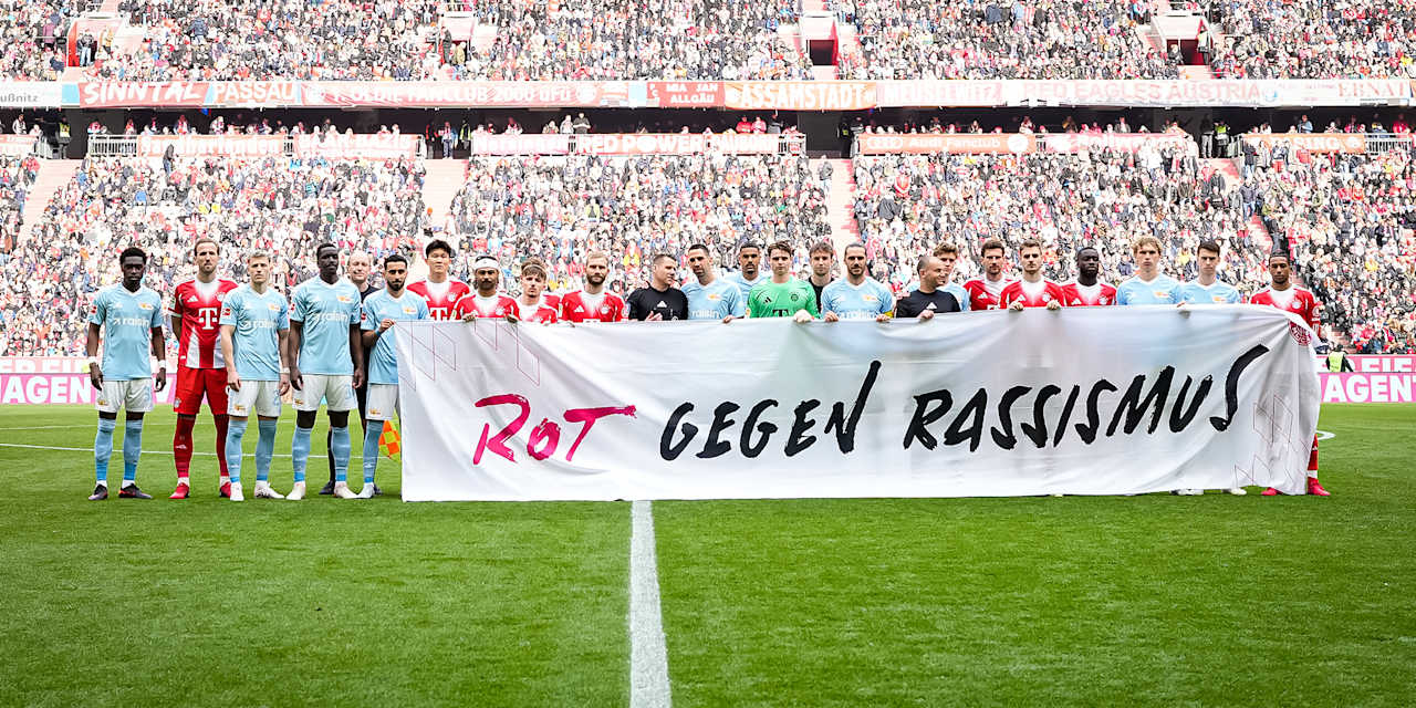 Die Spieler halten ein Banner mit der Aufschrift "Rot gegen Rassismus" vor dem Heimspiel des FC Bayern in der Bundesliga gegen den 1. FC Union Berlin