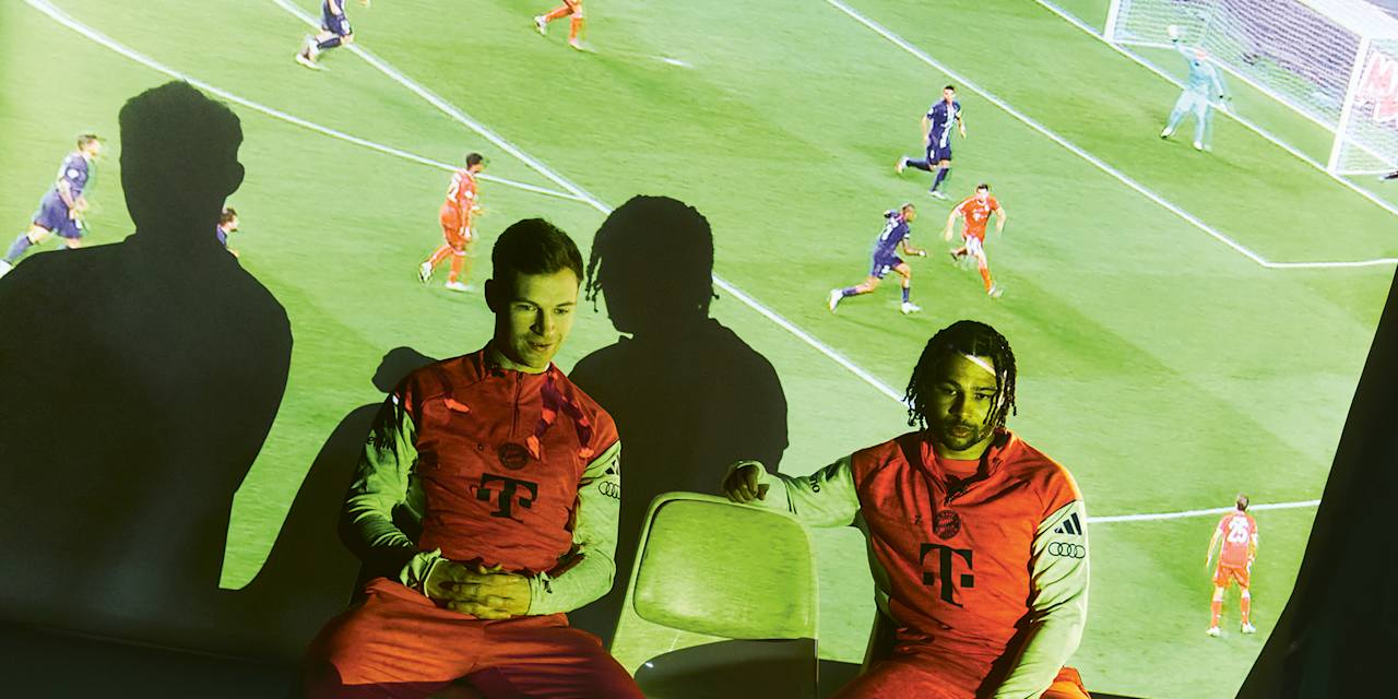 Joshua Kimmich und Serge Gnabry beim TV-Abend - auf einer Leinwand hinter ihnen sind Ausschnitte großer Bayern-Triumphe zu sehen