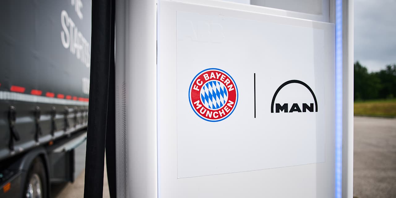 Logos des FC Bayern und MAN auf einer Ladesäule an der Allianz Arena