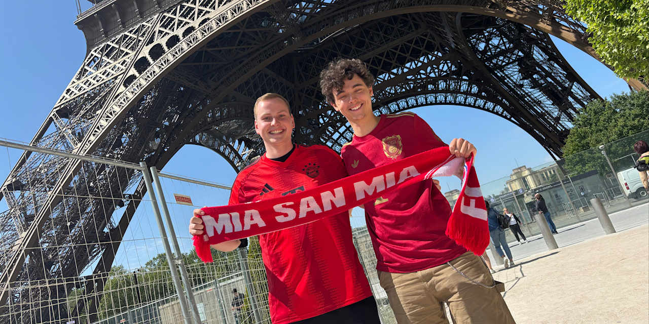 Zwei Bayern-Fans halten einen Schal hoch vor dem Eiffelturm in Paris