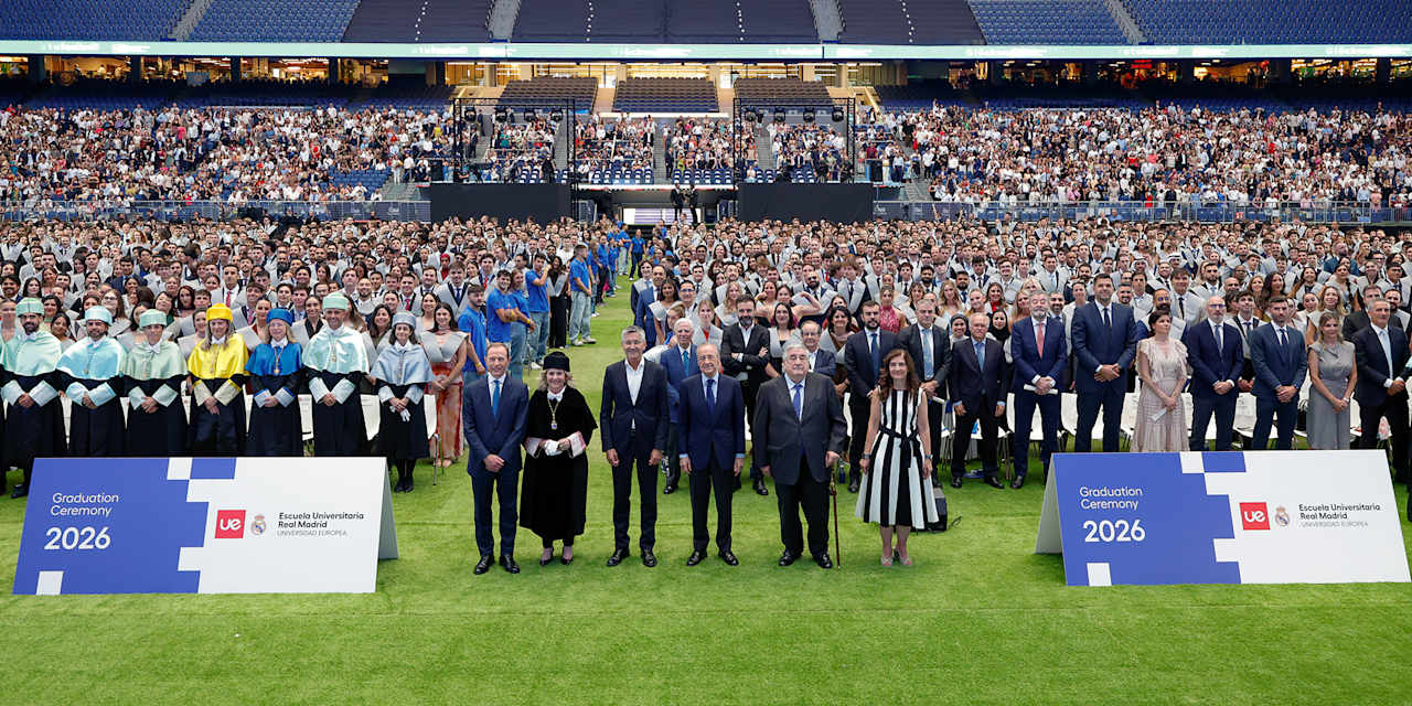 Herbert Hainer und Florentino Pérez stehen vor Universitätsabsolventen auf dem Rasen des Bernabéu