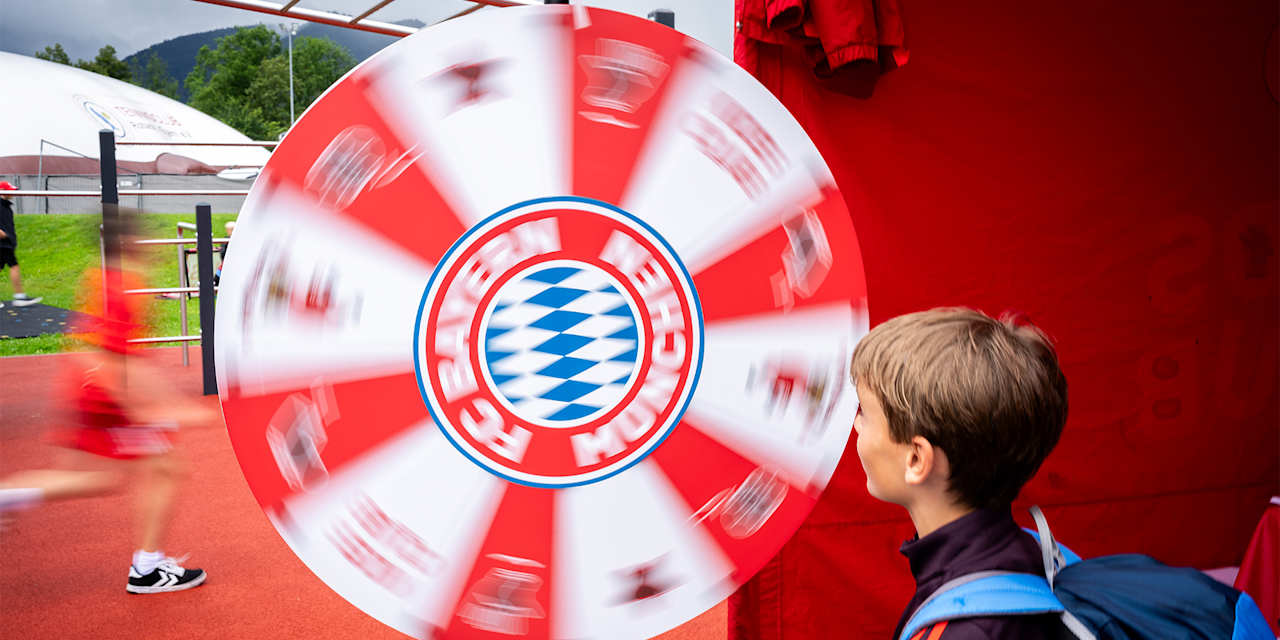 Ein Kind steht vor einem Glücksrad mit FC Bayern-Logo.