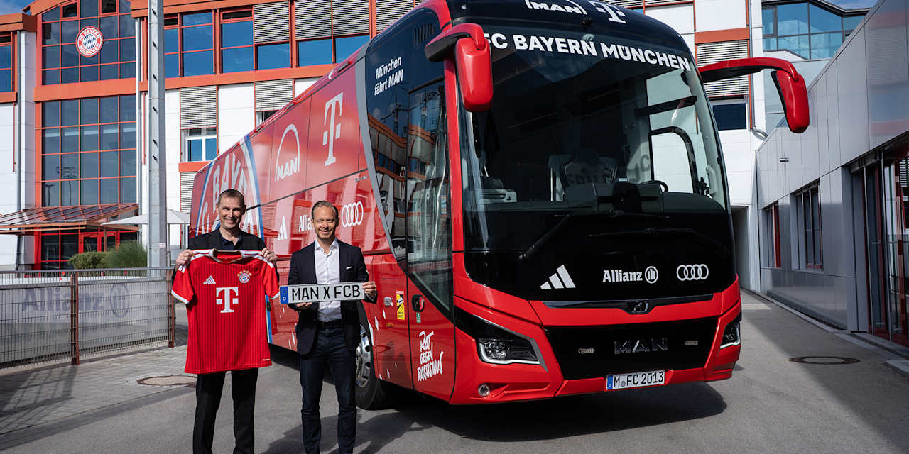 MAN-Vorstand Michael Kobriger und FC Bayern Marketing-Vorstand Rouven Kasper stehen vor dem neuen MAN-Mannschaftbus des FC Bayern an der Säbener Straße
