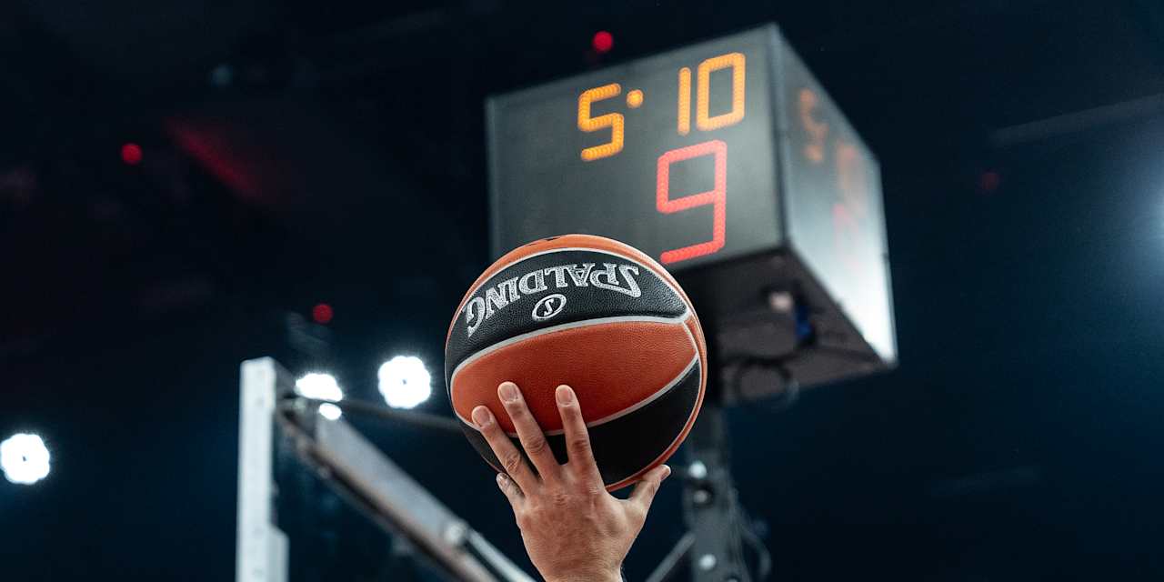 Hand hält den Ball der EuroLeague in Korbnähe