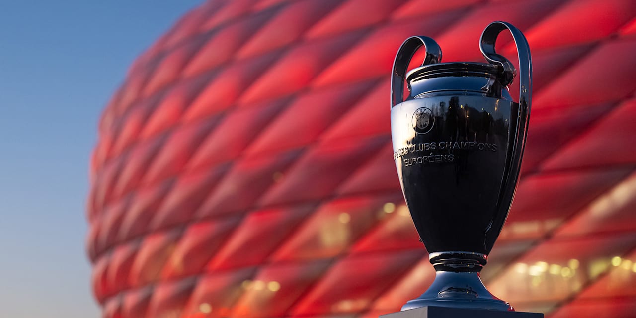 Der Champions League-Pokal vor der rot beleuchteten Allianz Arena