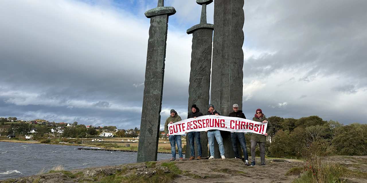 Bayern fans stand in front of the three swords in Stavanger with a get-well-soon banner