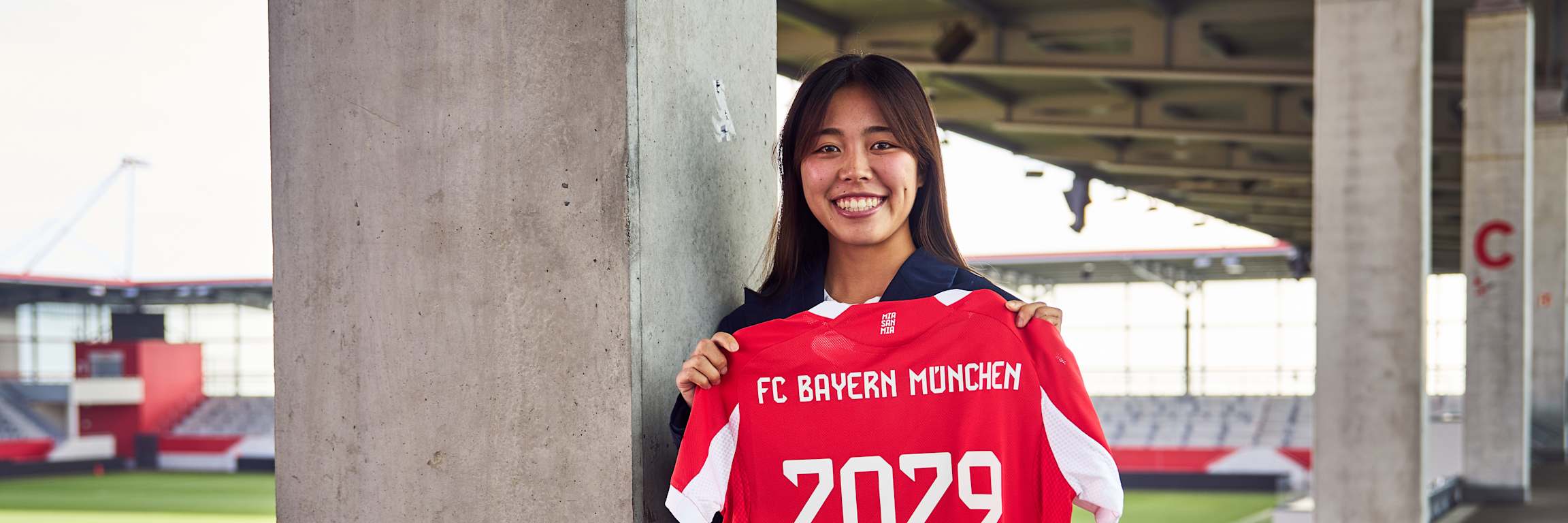 Momoko Tanikawa holds up her Bayern jersey with 2029 printed on the back.