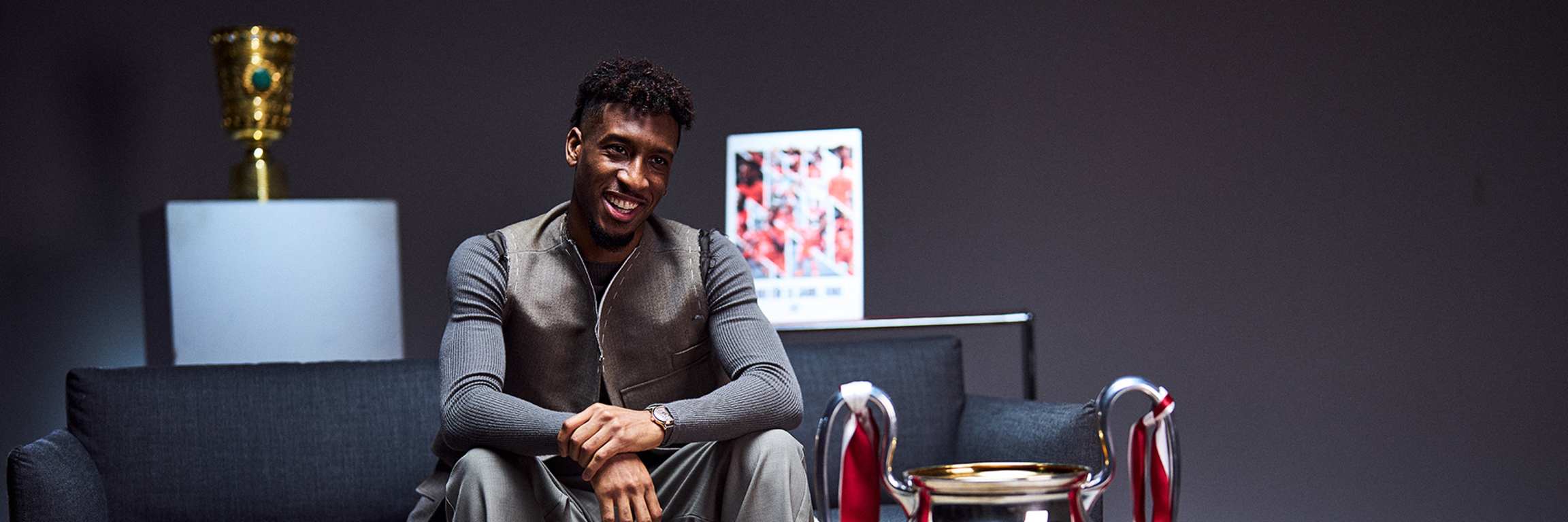 Kingsley Coman im Interview auf einer Couch, vor ihm der Champions League-Pokal