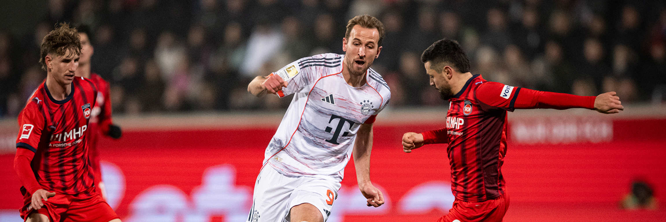 Harry Kane am Ball wird attackiert von seinem Gegenspieler im Bundesliga-Spiel des FC Bayern in Heidenheim.