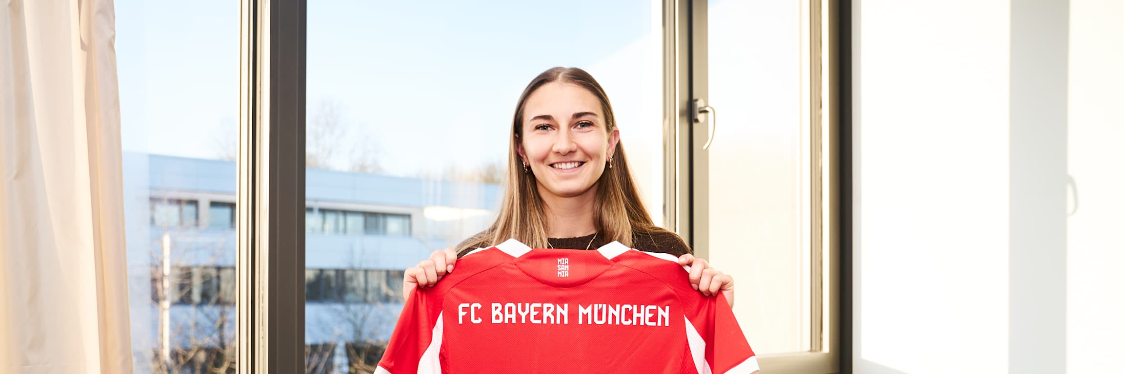 Katharina Naschenweng hält ihr Trikot mit ihrer neuen Vertragslaufzeit in den Händen.