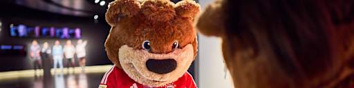 FC Bayern Maskottchen Berni malt ein Bild im FC Bayern Museum