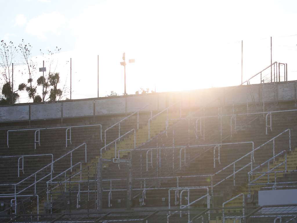 Die Sonne geht hinter der Tribüne am Grünwalder Stadion unter.