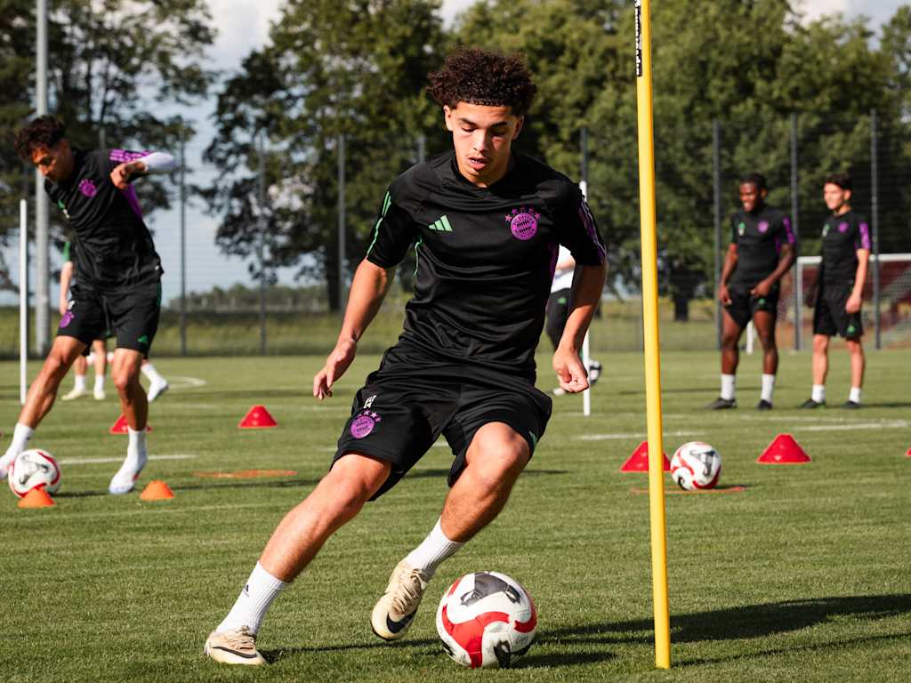 Ein Spieler der FC Bayern-Jugend umdribbelt eine Stange im Training mit dem Ball