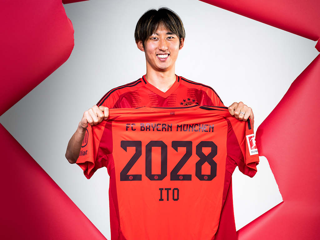 Hiroki Ito hält ein FC Bayern-Trikot mit der Zahl 2028 hoch.