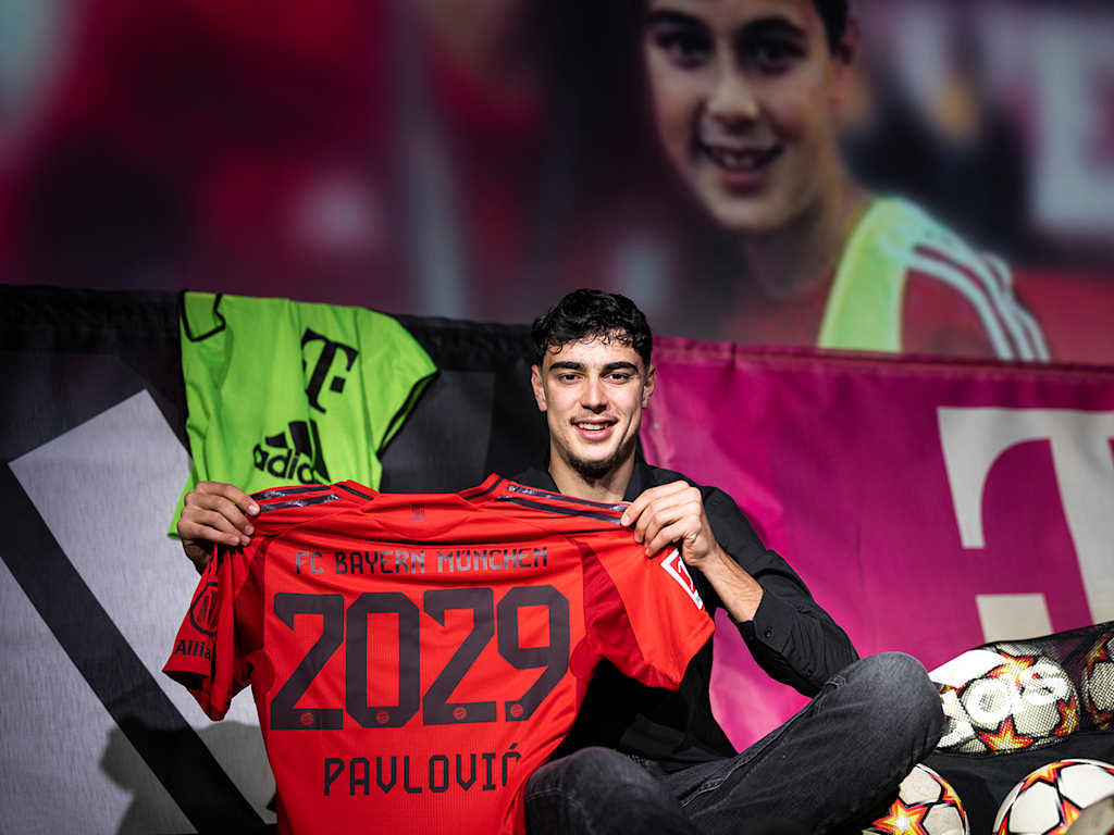 Pavlovic with an FC Bayern shirt marked 2029 in front of a picture from his youth days