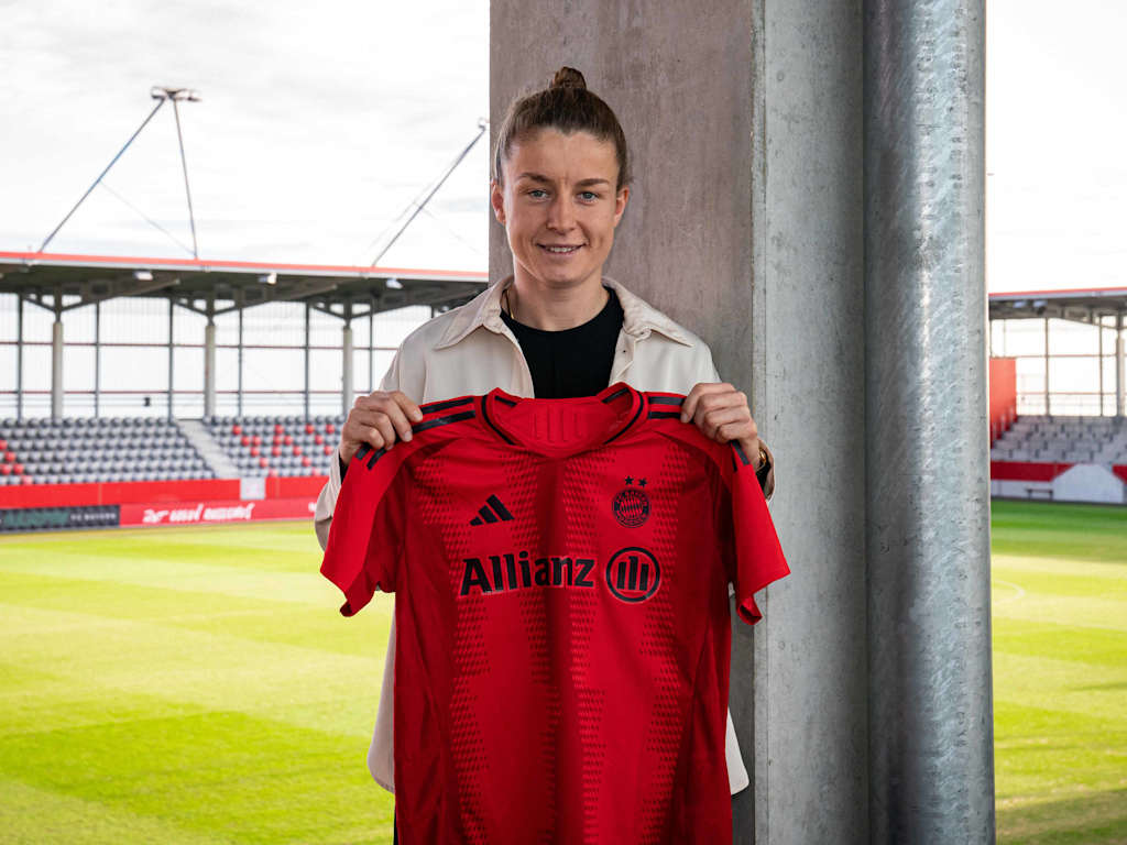 Michelle Ulbrich in the stands holding up an FC Bayern shirt for the camera