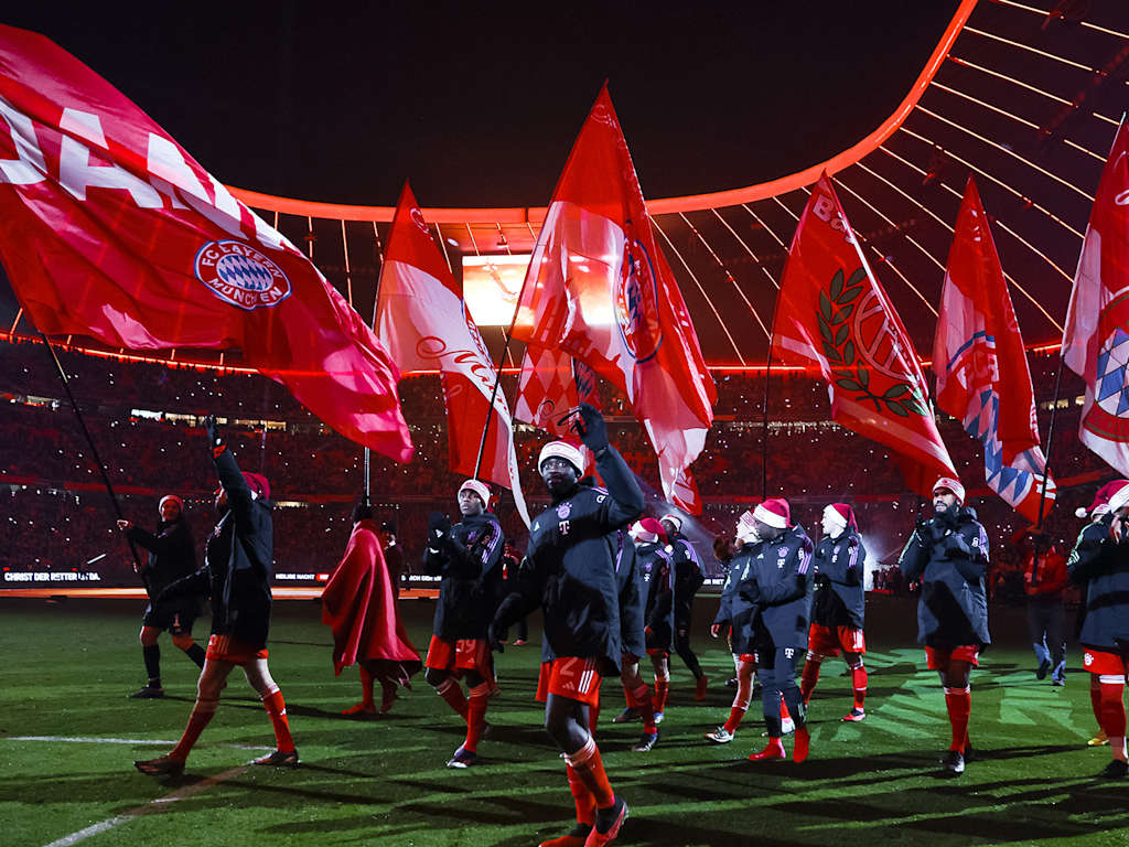 Nach dem letzten Heimspiel 2023 laufen die FC Bayern-Spieler mit Fahnen über den Rasen der Allianz Arena