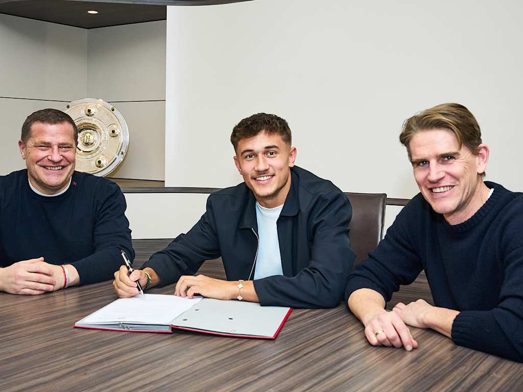 Tom Bischof unterschreibt seinen Vertrag beim FC Bayern. Neben ihm sitzen Max Eberl und Christoph Freund