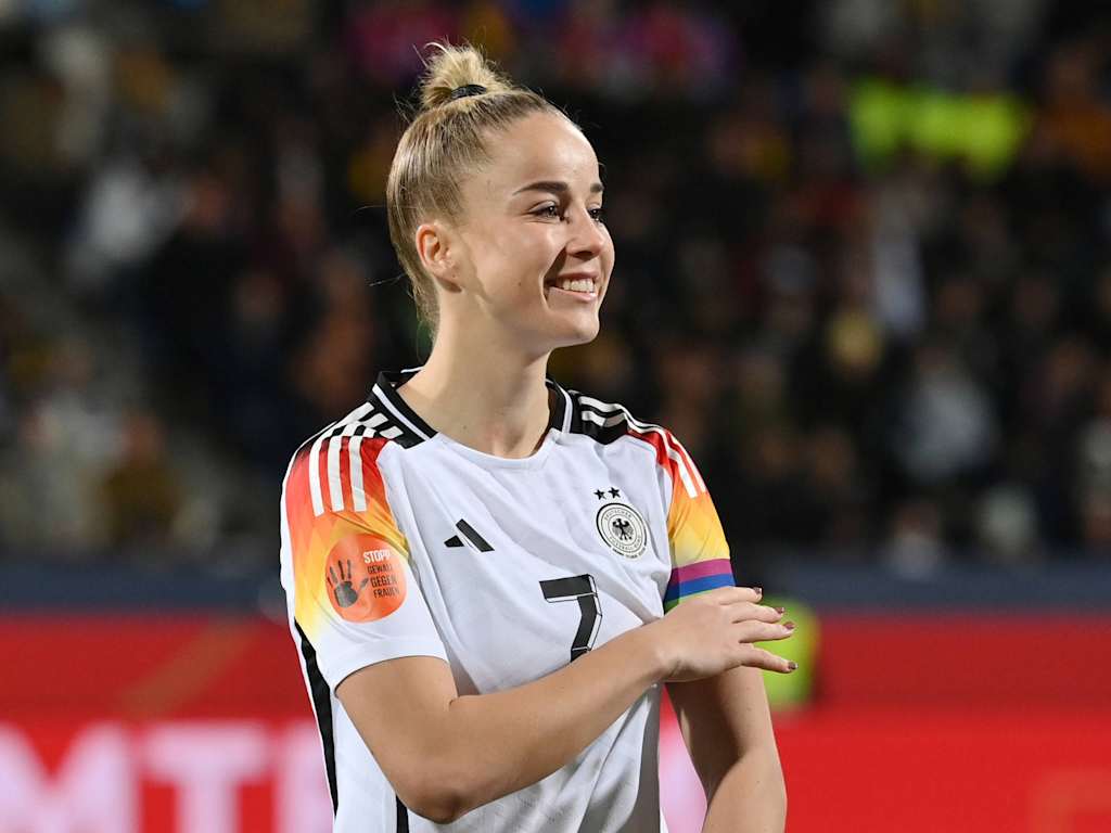 Giulia Gwinn im Trikot der deutschen Nationalmannschaft mit Kapitänsbinde am Arm und lächelt.
