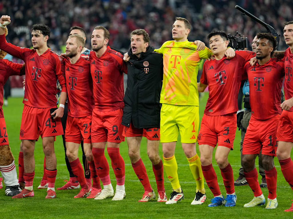 FC Bayern players celebrate arm in arm in front of the Südkurve.