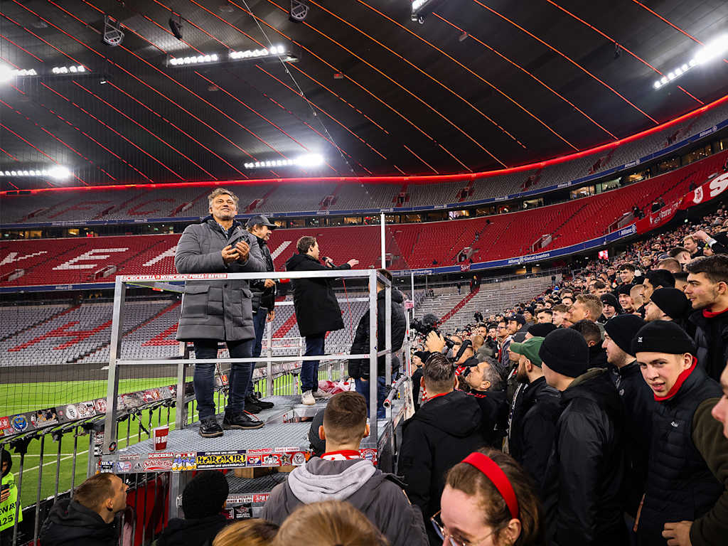 The star tenor Jonas Kaufmann looks down from a podium at the fans in the Südkurve at the Allianz Arena in Munich.