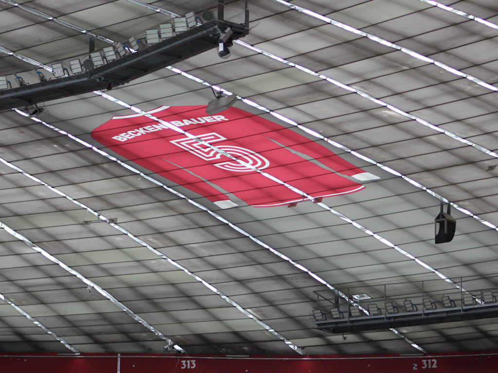 A red shirt with Franz Beckenbauer and a white number 5 hangs under the roof of the Allianz Arena