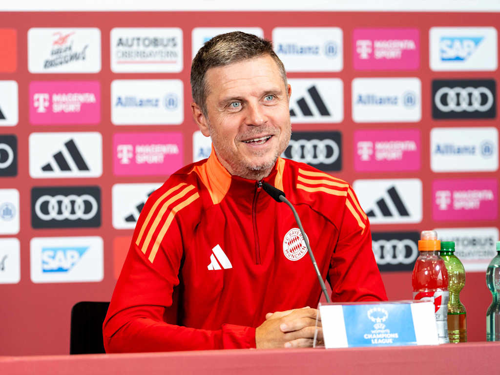 Alexander Straus sitzt im Pressekonferenz-Raum des FC Bayern.
