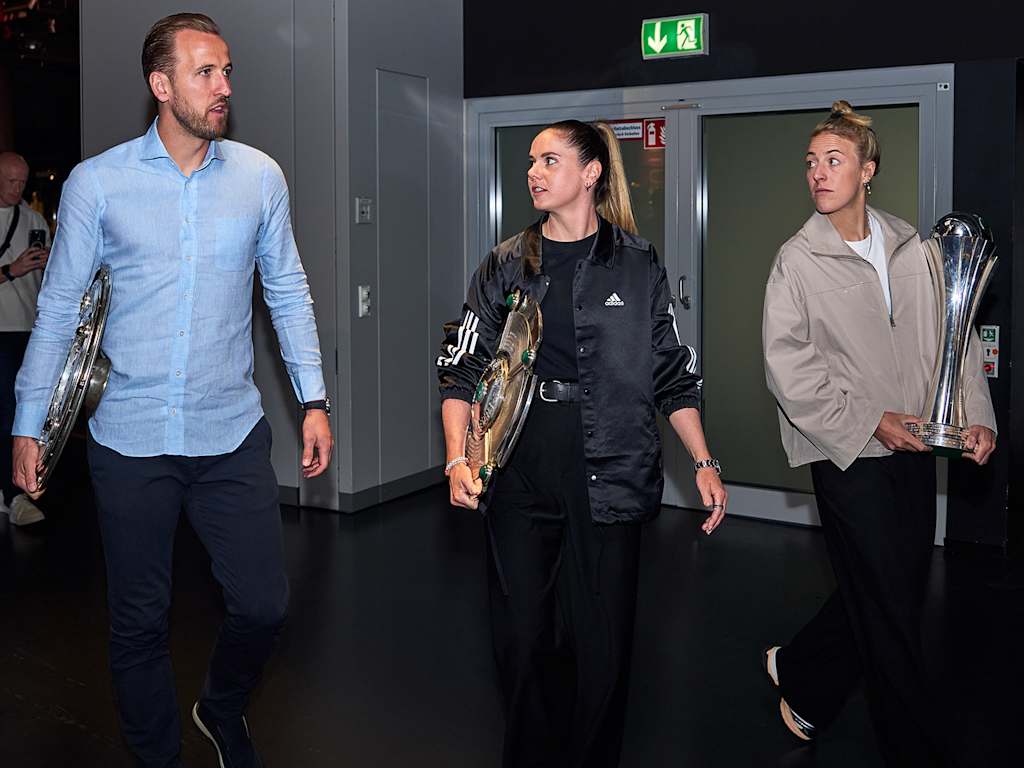 Harry Kane, Sarah Zadrazil und Caro Simon bringen die Trophäen des FC Bayern aus der Saison 2024/25 ins Vereinsmuseum.