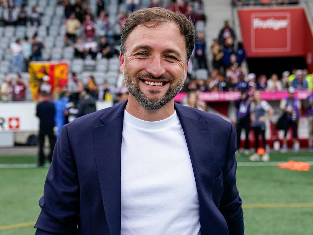Trainer José Barcala steht im Anzug im Stadion.