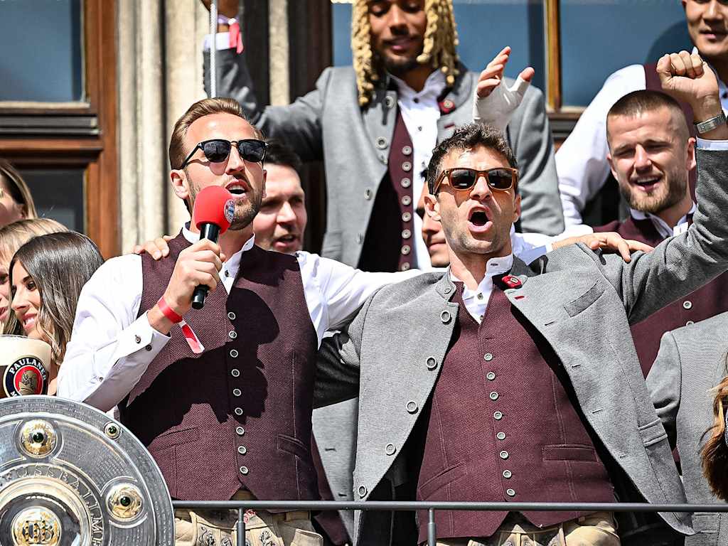 Harry Kane und Thomas Müller singen auf dem Rathausbalkon des Münchner Marienplatz