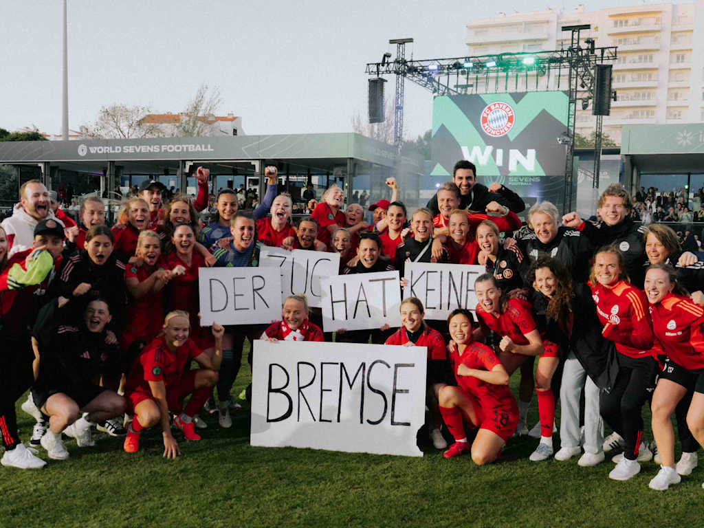 Die FC Bayern Frauen jubeln auf einem Gruppenfoto mit Schildern in der Hand, auf denen "Der Zug hat keine Bremse" steht.