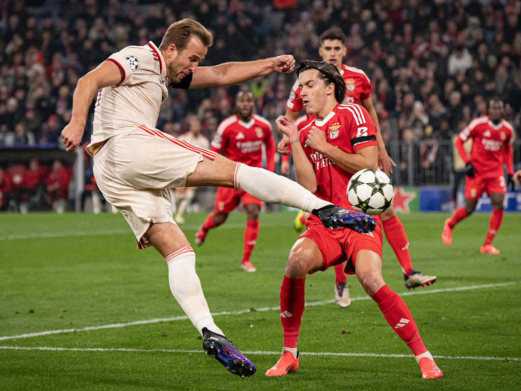 Harry Kane takes the ball first-time in the air, a Benfica defender tries to block