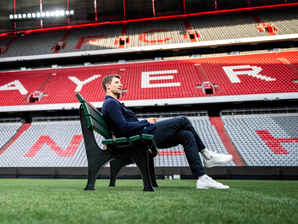 Thomas Müller sits in the Allianz Arena on a park bench on the pitch.