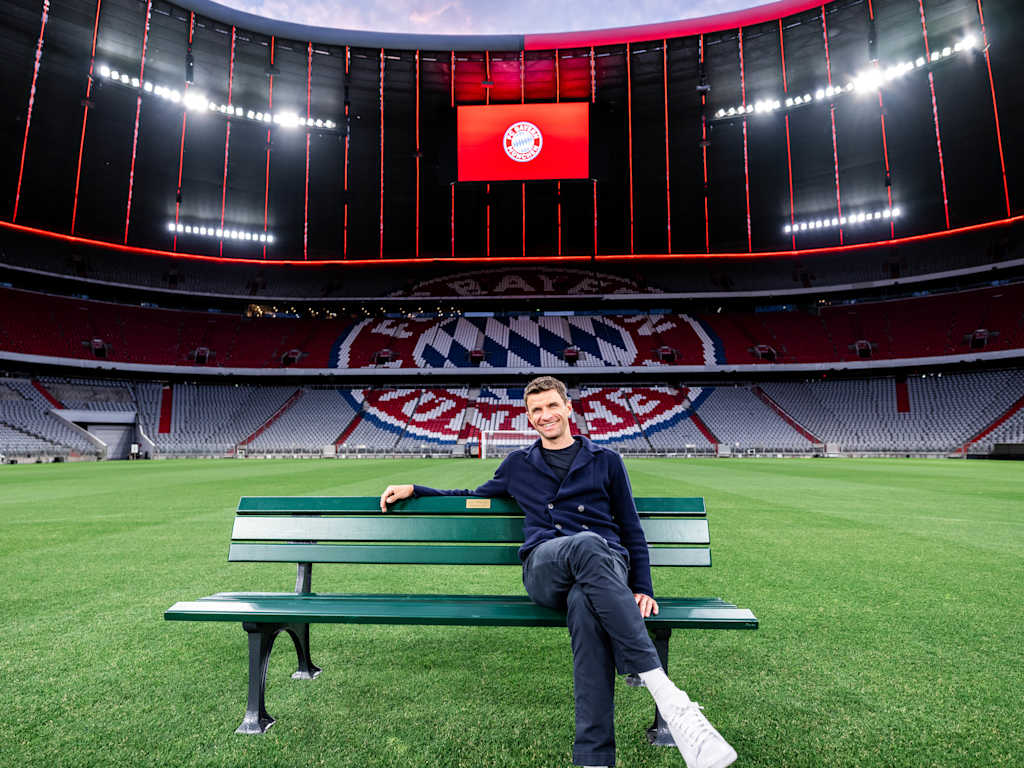 Thomas Müller sits in the Allianz Arena on a park bench on the pitch.