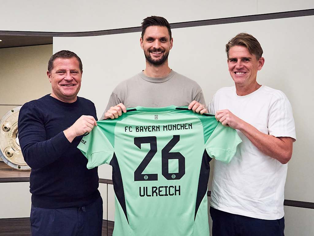 Max Eberl, Sven Ulreich and Christoph Freund hold up a goalkeeper jersey emblazoned with the number 26 and Ulreich