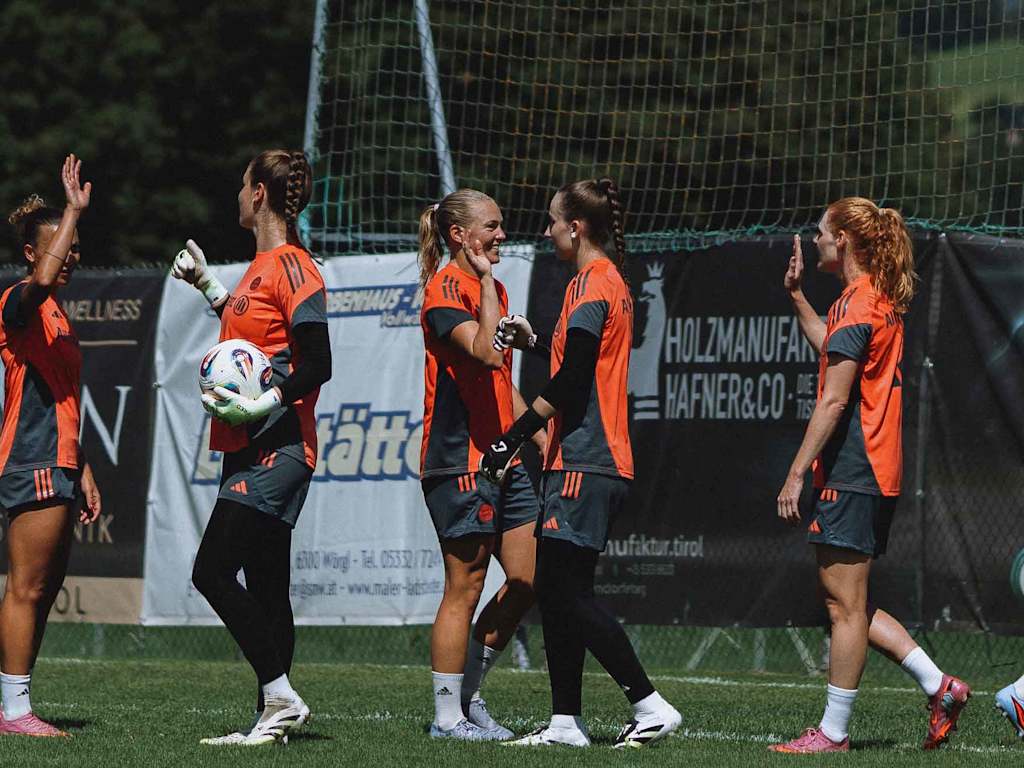 FC Bayern Women players high-five each other on the training pitch.