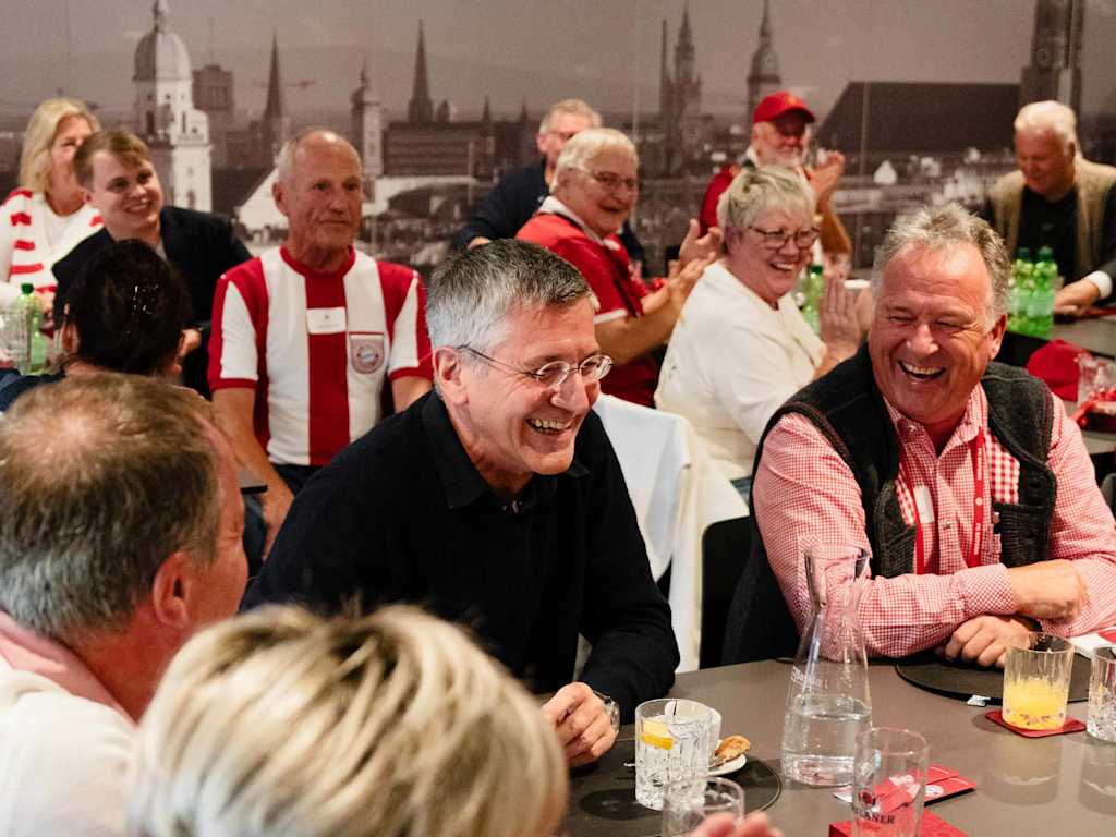Herbert Hainer lacht inmitten von FC Bayern-Fans