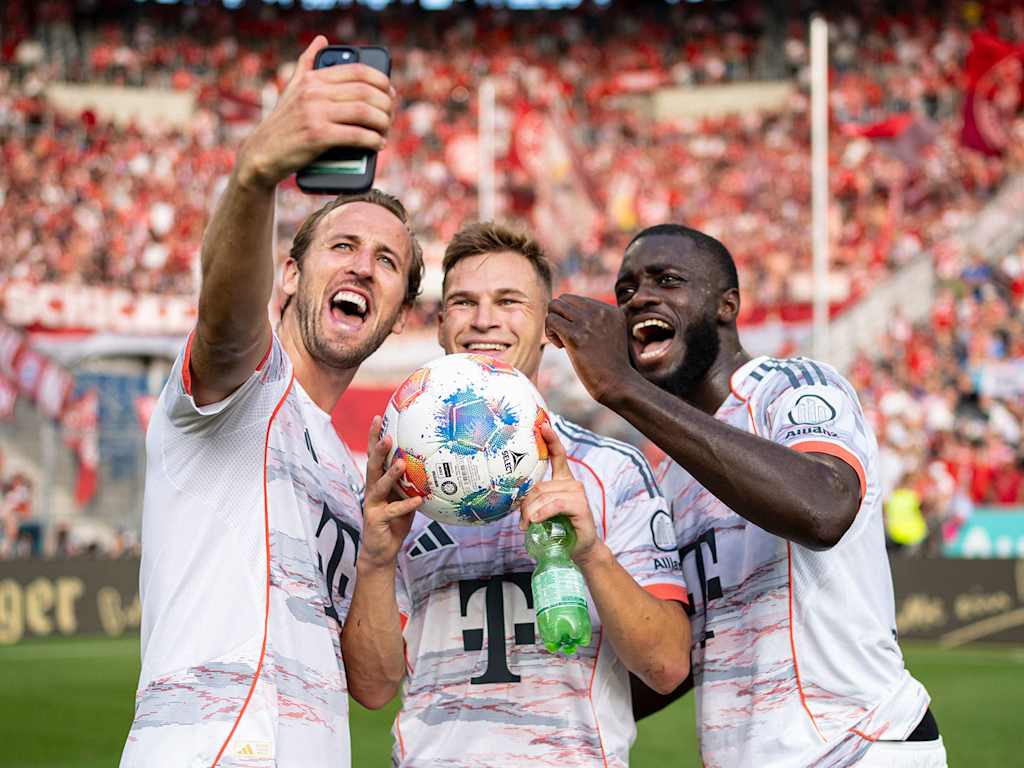 Harry Kane, Joshua Kimmich and Dayot Upamecano take a selfie in front of the visitors' block in Sinsheim in their white jerseys.