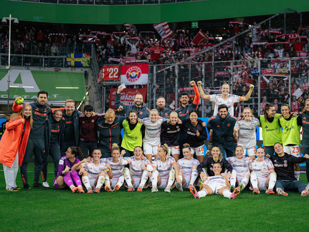 The celebrating team in a group photo in front of the FC Bayern fan section.