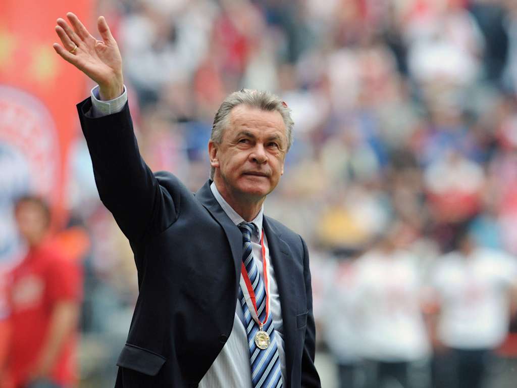 Ottmar Hitzfeld winkt ins Publikum, links eine Bayern-Fahne