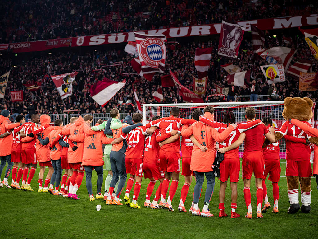 Spieler des FC Bayern hüpfen Arm in Arm vor der Südkurve nach dem Sieg gegen Freiburg.