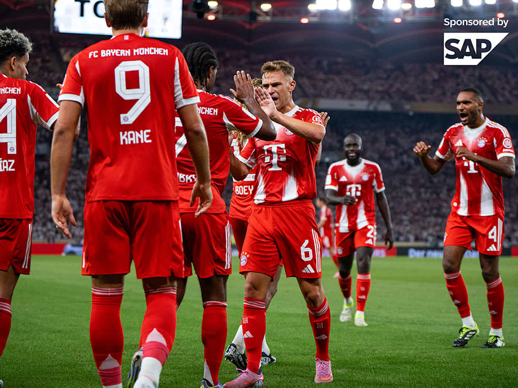 Joshua Kimmich surrounded by jubilant FC Bayern teammates celebrating in red jerseys