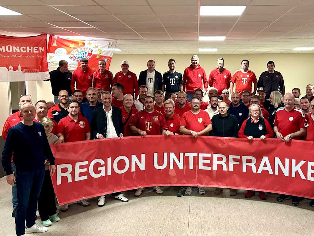 Bayernfans haben sich aufgereiht für die Kamera mit einem großen Banner "Region Unterfranken"