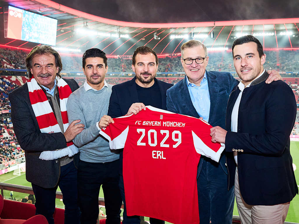 Jan-Christian Dreesen und Vertreter von ERL halten ein FC Bayern-Trikot mit dem Schriftzug 2029 ERL.
