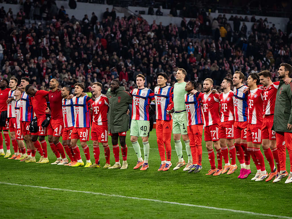 FC Bayern players celebrating with an FC Bayern fan after a match at the Allianz Arena.